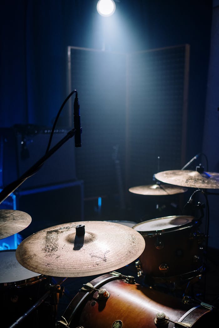 Close-up of a drum set in a dimly lit music studio with dramatic lighting.